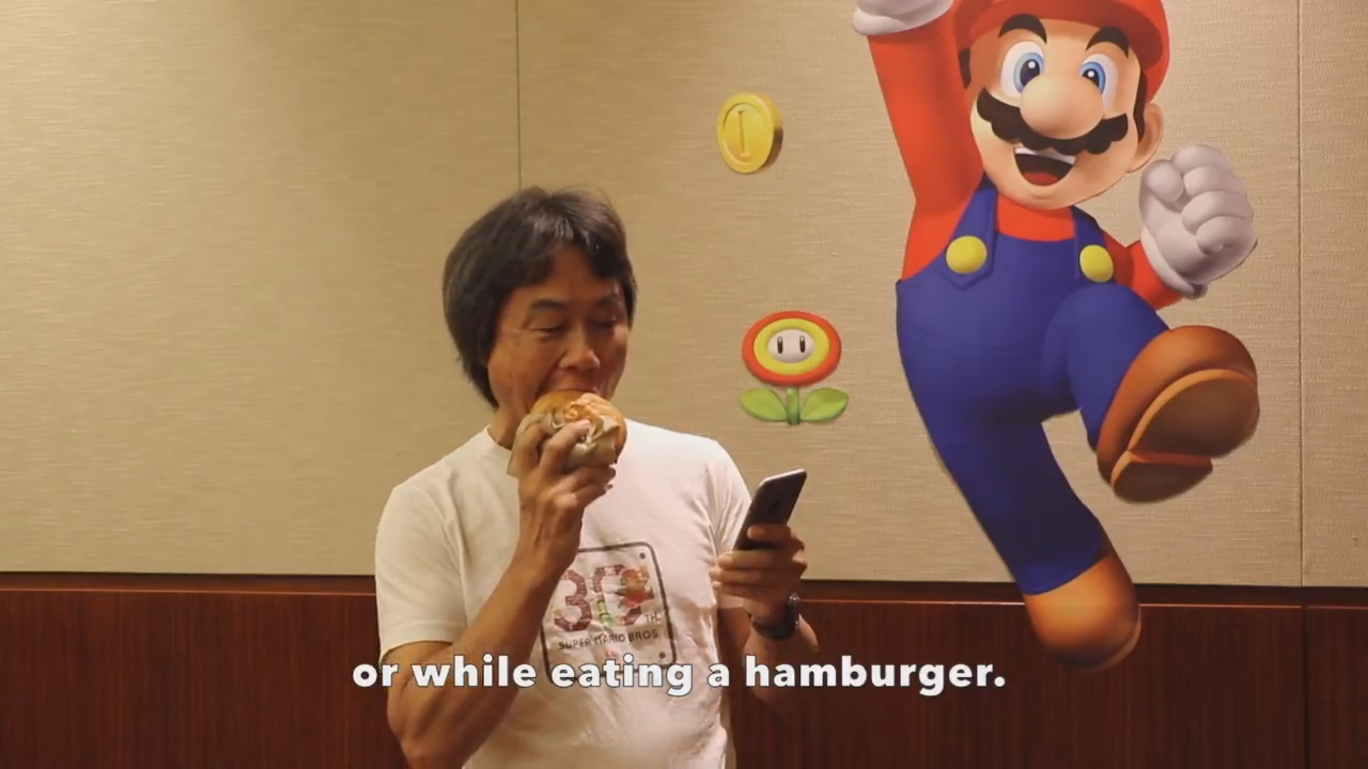 Miyamoto shows how to eat a burger while playing Super Mario Run